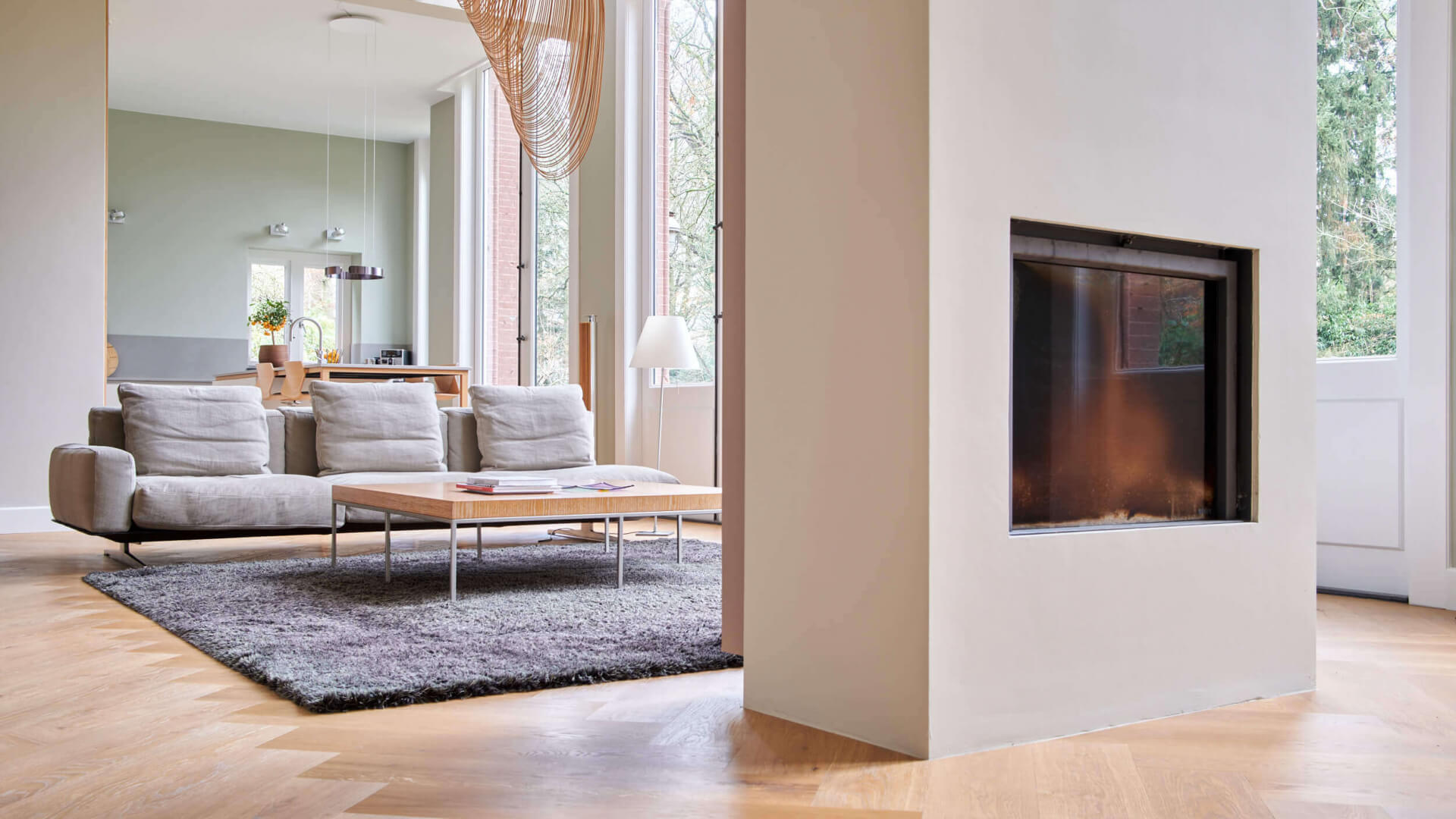 Beige visgraat vloer zonder plint, vakkundig gelegd rondom een pilaar voor een strak en naadloos design